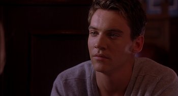 Movie still from “Match Point” (2005), directed by Woody Allen – A man sitting in front of a wooden wall; Close Up shot, Over the shoulder angle