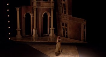 Movie still from “Match Point” (2005), directed by Woody Allen – A woman standing on a stage in front of a building; Extreme Wide shot, High angle