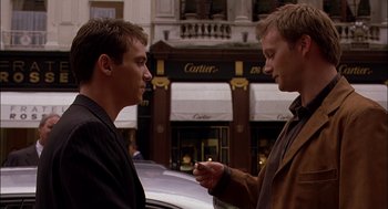 Movie still from “Match Point” (2005), directed by Woody Allen – Two young men standing next to each other on the street; Close Up shot, Over the shoulder angle