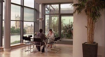 Movie still from “Match Point” (2005), directed by Woody Allen – Two people sitting at a table in front of a large window; Wide shot, Over the shoulder angle