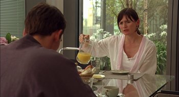 Movie still from “Match Point” (2005), directed by Woody Allen – A man and a woman sitting at a table with a bowl of orange juice; Medium shot, Over the shoulder angle