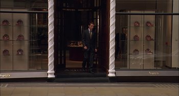 Movie still from “Match Point” (2005), directed by Woody Allen – A man in a suit and tie walking down a street; Wide shot, Over the shoulder angle