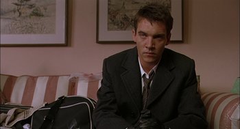 Movie still from “Match Point” (2005), directed by Woody Allen – A man sitting on a couch in a suit and tie; Close Up shot, Low angle