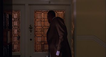 Movie still from “Match Point” (2005), directed by Woody Allen – A man standing in front of an open front door; Medium shot, Low angle