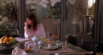 Movie still from “Match Point” (2005), directed by Woody Allen – A woman sitting at a table with a plate of food on top of it; Medium shot, Over the shoulder angle