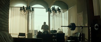 Movie still from “Matchstick Men” (2003), directed by Ridley Scott – A man sitting at a desk in front of a large window; Wide shot, Low angle
