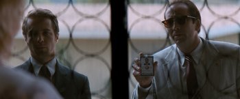 Movie still from “Matchstick Men” (2003), directed by Ridley Scott – A man holding a cell phone in front of a barred window; Close Up shot, Over the shoulder angle