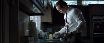 Movie still from “Matchstick Men” (2003), directed by Ridley Scott – A man in white shirt and tie pouring a cup of coffee; Medium shot, Low angle