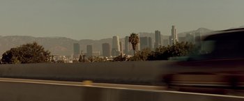 Movie still from “Matchstick Men” (2003), directed by Ridley Scott – A view of a city skyline from the side of a freeway; Extreme Wide shot, Low angle