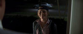 Movie still from “Matchstick Men” (2003), directed by Ridley Scott – A woman smiling for the camera wearing a hat; Medium shot, Over the shoulder angle