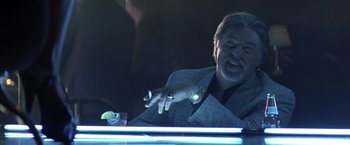 Movie still from “Matchstick Men” (2003), directed by Ridley Scott – An older man sitting at a table holding a cell phone; Close Up shot, Low angle