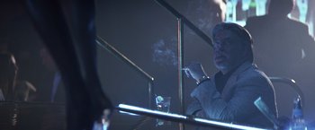 Movie still from “Matchstick Men” (2003), directed by Ridley Scott – An older man smoking a cigarette on the stairs; Medium shot, Low angle