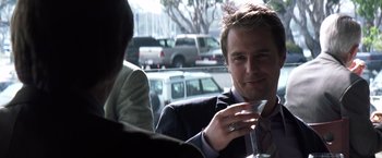 Movie still from “Matchstick Men” (2003), directed by Ridley Scott – A man sitting at a table holding a wine glass; Close Up shot, Over the shoulder angle