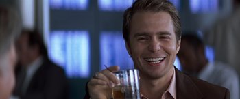 Movie still from “Matchstick Men” (2003), directed by Ridley Scott – A smiling man holding a glass of beverage; Close Up shot, Over the shoulder angle