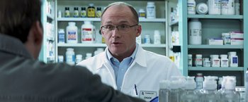 Movie still from “Matchstick Men” (2003), directed by Ridley Scott – A man in white lab coat talking to a person; Close Up shot, Over the shoulder angle