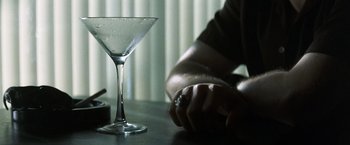 Movie still from “Matchstick Men” (2003), directed by Ridley Scott – A person sitting at a table with an empty martini glass; Extreme Close Up shot, High angle