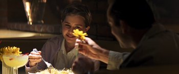 Movie still from “Matchstick Men” (2003), directed by Ridley Scott – A man holding a flower in front of a boy; Close Up shot, Over the shoulder angle