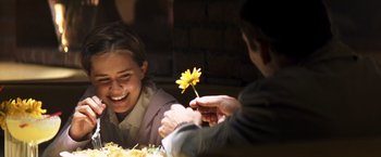 Movie still from “Matchstick Men” (2003), directed by Ridley Scott – A man holding a yellow flower in front of a smiling woman; Close Up shot, Over the shoulder angle