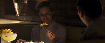 Movie still from “Matchstick Men” (2003), directed by Ridley Scott – A woman holding a yellow flower in front of a cake; Close Up shot, Over the shoulder angle