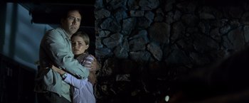 Movie still from “Matchstick Men” (2003), directed by Ridley Scott – A man and a woman holding each other in front of a stone wall; Medium shot, Over the shoulder angle