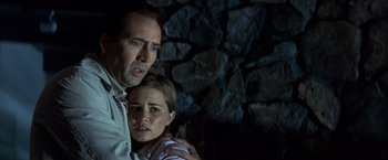 Movie still from “Matchstick Men” (2003), directed by Ridley Scott – A man and a woman are standing next to each other in front of a stone wall; Close Up shot, Low angle