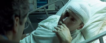 Movie still from “Matchstick Men” (2003), directed by Ridley Scott – A man laying in a hospital bed with his hand to his face; Close Up shot, High angle