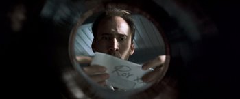 Movie still from “Matchstick Men” (2003), directed by Ridley Scott – A man holding a piece of paper up to his face; Extreme Close Up shot, Overhead angle
