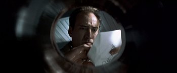 Movie still from “Matchstick Men” (2003), directed by Ridley Scott – A man looking at a piece of paper through a round mirror; Extreme Close Up shot, Low angle