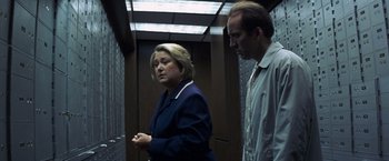 Movie still from “Matchstick Men” (2003), directed by Ridley Scott – A woman and a man standing next to each other in an elevator; Medium shot, Low angle