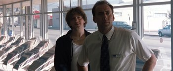 Movie still from “Matchstick Men” (2003), directed by Ridley Scott – A man standing next to another man in front of a window; Close Up shot, Low angle