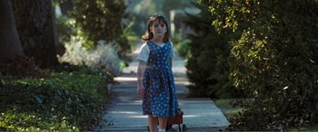 Movie still from “Matilda” (1996), directed by Danny DeVito – A little girl in a blue dress is walking down the sidewalk; Wide shot, High angle