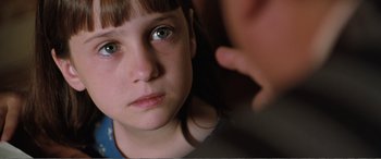 Movie still from “Matilda” (1996), directed by Danny DeVito – A young girl looking into a mirror with a hand on her ear; Close Up shot, Over the shoulder angle