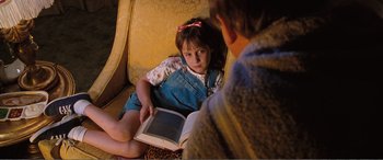 Movie still from “Matilda” (1996), directed by Danny DeVito – A little girl sitting next to a man reading a book; Medium shot, High angle