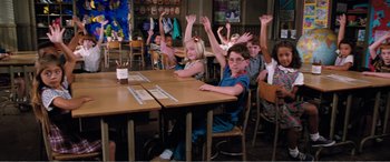 Movie still from “Matilda” (1996), directed by Danny DeVito – A group of children sitting at a table with their hands raised; Medium shot, High angle