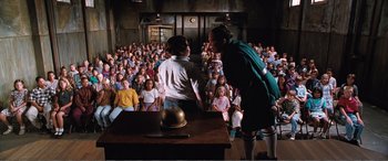 Movie still from “Matilda” (1996), directed by Danny DeVito – A group of people standing in front of an audience; Wide shot, High angle