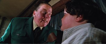 Movie still from “Matilda” (1996), directed by Danny DeVito – A man in a green suit talking to a boy in a white shirt; Close Up shot, Low angle