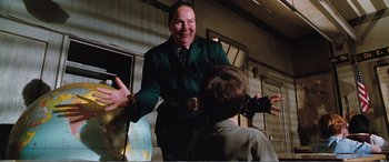Movie still from “Matilda” (1996), directed by Danny DeVito – A man in a green suit is talking to a boy in a green suit; Medium shot, Over the shoulder angle