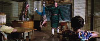 Movie still from “Matilda” (1996), directed by Danny DeVito – A man hanging upside down in front of a girl; Wide shot, Low angle