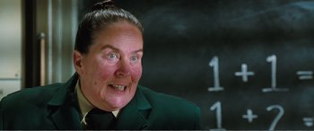 Movie still from “Matilda” (1996), directed by Danny DeVito – A woman in a green jacket is smiling for the camera; Close Up shot, Over the shoulder angle