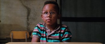 Movie still from “Matilda” (1996), directed by Danny DeVito – A young boy wearing glasses sitting at a table; Close Up shot, High angle