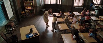 Movie still from “Matilda” (1996), directed by Danny DeVito – A woman helping a boy to put on a jacket in a classroom; Wide shot, High angle
