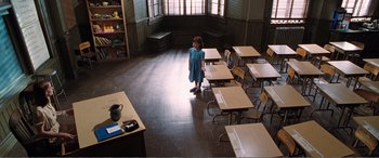 Movie still from “Matilda” (1996), directed by Danny DeVito – A little girl standing in front of a bunch of desks in a classroom; Wide shot, High angle