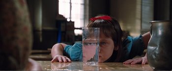 Movie still from “Matilda” (1996), directed by Danny DeVito – A little girl looking into a glass of water; Close Up shot, Over the shoulder angle