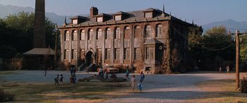 Movie still from “Matilda” (1996), directed by Danny DeVito – A group of people standing in front of an old building; Extreme Wide shot, High angle