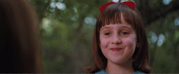 Movie still from “Matilda” (1996), directed by Danny DeVito – A young girl smiling for the camera; Close Up shot, High angle