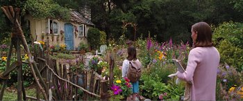 Movie still from “Matilda” (1996), directed by Danny DeVito – A girl with a backpack standing in a flower garden; Wide shot, High angle