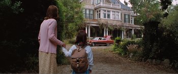 Movie still from “Matilda” (1996), directed by Danny DeVito – A woman and a girl holding hands in front of a house; Wide shot, Low angle