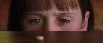 Movie still from “Matilda” (1996), directed by Danny DeVito – A person's eyes with a piece of food in front of them; Extreme Close Up shot, High angle
