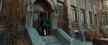 Movie still from “Matilda” (1996), directed by Danny DeVito – A woman in a green dress walking down the steps of a building; Wide shot, Low angle