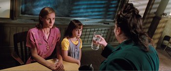 Movie still from “Matilda” (1996), directed by Danny DeVito – A woman holding a glass in front of two young girls; Medium shot, Over the shoulder angle